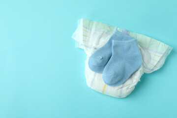 Diaper with baby socks on blue background