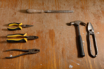 Old tools pliers, hammer, file, scissors on a dirty wooden table