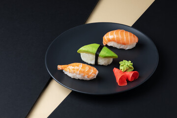 Japanese cuisine - set of nigiri sushi with salmon, avocado ans schrimp on a black plate.