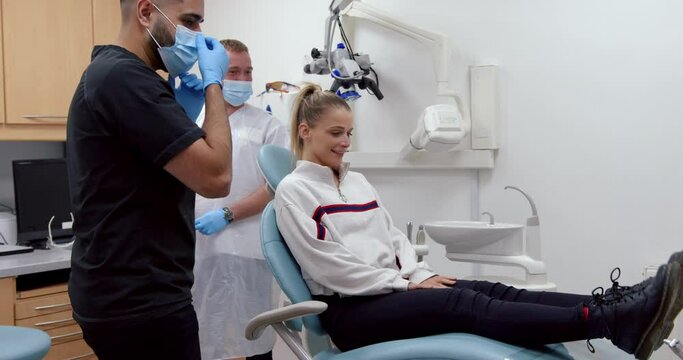 Caucasian female patient lying on doctors bed while male nurse moves dental tools