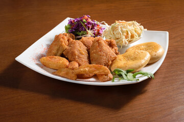 Pieces of chicken fillet fried in batter on a plate with potatoes, bread and salad
