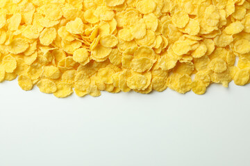 Dry uncooked corn flakes on white background, space for text