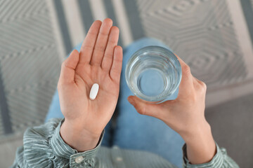 Young woman with abortion pill and glass of water, top view - obrazy, fototapety, plakaty