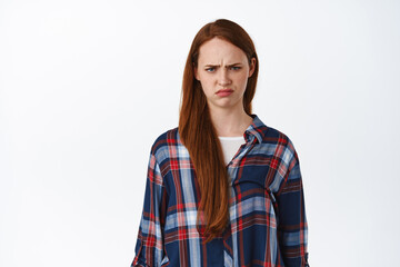 Portrait of grumpy and angry redhead woman, look hurt at unfair thing, frowning and sulking,...