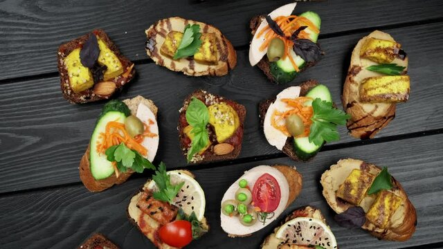 Delicious snacks. Bruschetta snacks. Variety of small sandwiches with vegetables - tomato, arugula, pepper. view from above. top view. black wood background