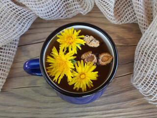 Dandelion grass root and flowers, herbal tea in a mug on wooden table, flat layout. Medicinal plant...