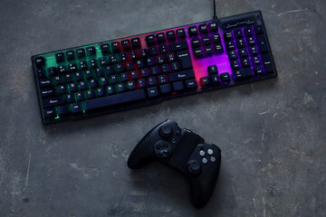 Modern RGB keyboard and game pad on grey table, flat lay