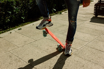 Young guy in ripped jeans standing with penny board in the park. summer activities skateboarding