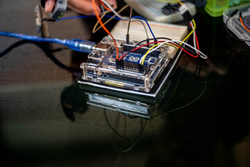 Close-up of Arduino equipment with colorful jumper wires connected to a breadboard, placed on a...