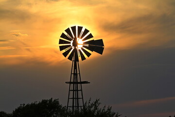 Kansas colorful Sunset with a Windmill silhouette and a colorful sky north of Hutchinson Kansas USA out in the country.