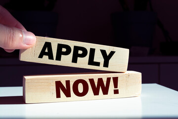 APPLY NOW! symbol. Wooden blocks with words 'APPLY NOW!' on beautiful orange background....
