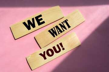 We want you! words on wooden blocks on pink background.