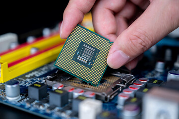 Hand with CPU on a computer motherboard.