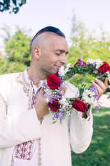 Young man posing in traditional folk costume. Cossack male in a wreath and embroidered shirts....