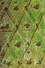 Fragment of an ancient wrought-iron medieval metal reliable door with decorative figures, painted in many layers mainly in shades of green