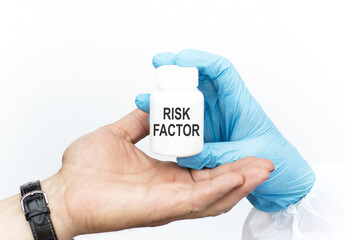 Doctor hands over to the patient a jar with medicine on which the inscription with Risk Factor, close-up of hands on a white background Medical concept.