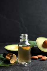 Essential oil, avocado and almonds on black table. Space for text