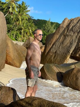 Jeune homme en maillot devant des rochers sur la plage