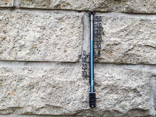 Closeup of a wall thermometer on a brick wall outdoors
