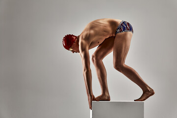 Swimmer man preparing to jump, young athlete, swimmer on a gray background, swimming healthy lifestyle, willingness to achieve success