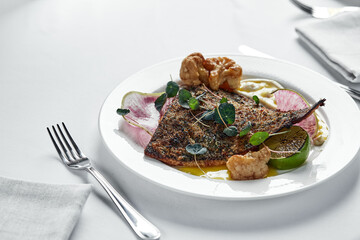 Grilled fish with vegetables on a white plate, fish flounder with cauliflower, radish and mashed potatoes, close-up