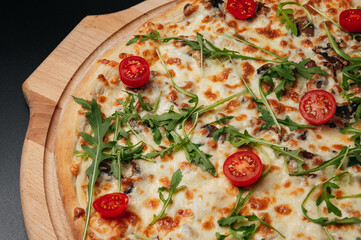 Italian food. Classic pizza with large sides, mushrooms, cherry tomatoes, arugula, parmesan cheese on wooden board