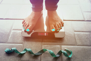 Selective focus of measure tape which woman feet look Lose weight concept  on a scale measuring...