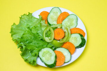 Delicious vegetable salad on a yellow background. Healthy diet food made from fresh vegetables. Vegetarian food