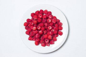 Raspberries in a plate on a white background. Red ripe raspberries close-up. Delicious berry