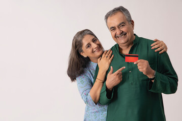 A HAPPY ADULT COUPLE STANDING WITH EACH OTHER WHILE HOLDING DEBIT CARD