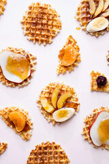 Belgian traditional waffles with various topping. Flat lay of waffles with honey and slice of various fruits. Sweet food, dessert background.