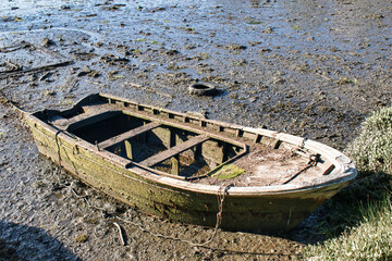 Vieja y abandonada barca a remos varada en la orilla de la desembocadura del río Verdugo durante...