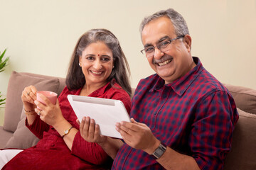 A HAPPY COUPLE SITTING WITH EACH OTHER AND HAPPILY LOOKING AT CAMERA