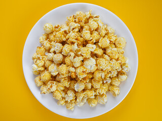 Thai style caramel baked popcorn, arranged on a white plate. with a yellow background.