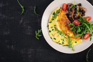 Omelette with cheese, green herbs and fried mushrooms on plate.  Frittata - italian omelet. Top view, above, copy space