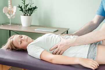 Osteopath practitioner releasing the diaphragm of a female patient, rib cage release massage,...
