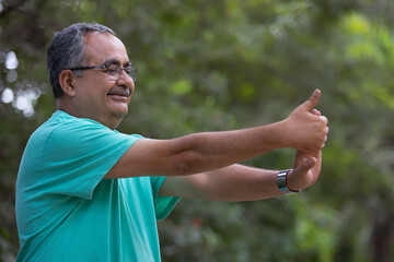 A SENIOR ADULT MAN HAPPILY EXCERCISING IN A PARK