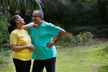 A  HAPPY OLD COUPLE TALKING TO EACH OTHER WHILE STANDING IN A PARK