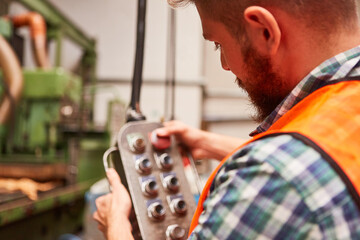 Arbeiter bedient Knöpfe an der Steuerung einer Maschine