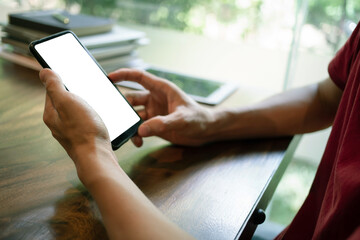 Man hand holding a smartphone with Mockup, a blank black screen in the coffee shop. Close up