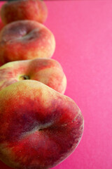 nearby are several pink peach figs lying on the left against a pink background. side view