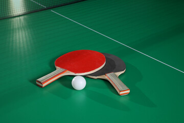 Rackets and ball on green ping pong table
