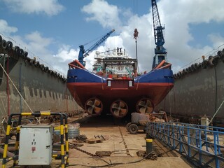 Maritime industry - Ocean Vessel in a dry dock in shipyard. View from aft, ship with 3 propellers.