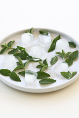 Fresh mint leaves and ice cubes on plate isolated on white background. Copy space.