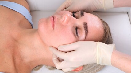 Facial massage beauty treatment. Close up of a young womans face lying on back, getting face lifting massage, pinch and roll technique