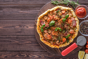 Pizza with shrimps, cheese, basil and tomatoes on a wooden background