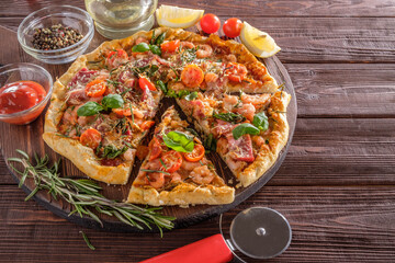 Pizza with shrimps, cheese, basil and tomatoes on a wooden background