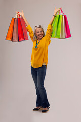 An old woman happily holding colorful carrybags.