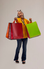 An old woman happily holding colorful carrybags.