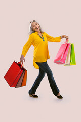 An old woman happily holding colorful carrybags.